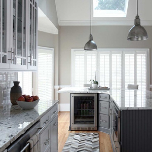 Clean, white kitchen with granite counter tops, subway tiles, and decorative mosaic tile